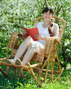 junge Frau liest im Garten-Schaukelstuhl